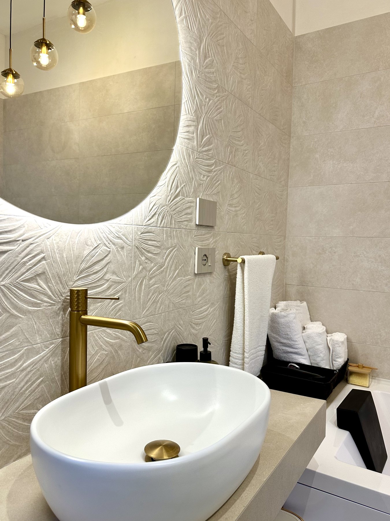 Il lavabo a bacinella con rubinetteria dorata e parete a rilievo